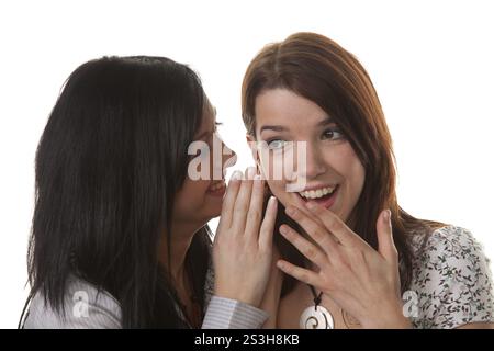 Zwei junge Mädchen flüstern einander die neuesten Nachrichten zu Stockfoto