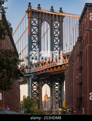Das Empire State Building ist perfekt eingerahmt von der Manhattan Bridge, die von der Washington Street in DUMBO, Brooklyn, aufgenommen wurde – eine ikonische New Yorker Perspektive. Stockfoto