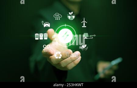 Konzept der grünen Energie. Ein Mann mit einem Smartphone, der Symbole nachhaltiger erneuerbarer Energiequellen in der Hand hält. Stockfoto