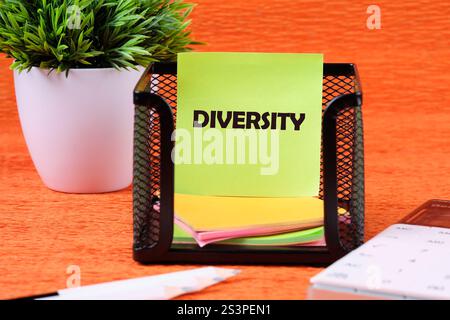 Business, Inklusion und Diversität. Kopierbereich. DIVERSITY-Wort auf einem grünen Aufkleber in einem Ständer auf orangefarbenem Hintergrund. Stockfoto