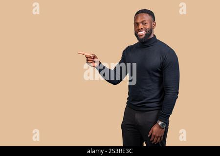 Studio-Porträt eines fröhlichen jungen Geschäftsmannes, der mit dem Finger zur Seite zeigt, während er in die Kamera lächelt Stockfoto