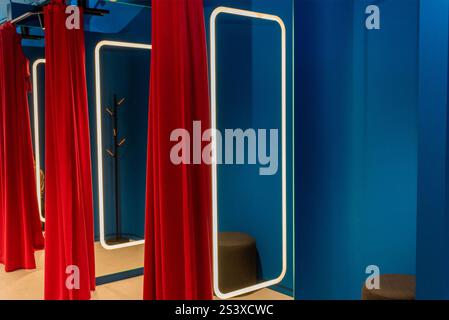 Ankleidezimmer in einem stilvollen Bekleidungsgeschäft, Ankleidezimmer mit roten Vorhängen und einem großen Spiegel Stockfoto