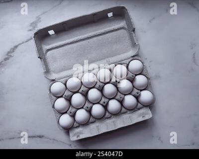 Blick von über 18 weißen Eiern in Eierkarton auf Marmoroberfläche Stockfoto