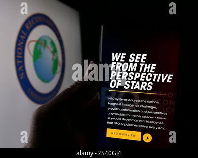 In dieser Fotoabbildung hält eine Person ein Handy mit der Webseite des National Reconnaissance Office (NRO) der US-Agentur auf dem Bildschirm mit Logo. Stockfoto