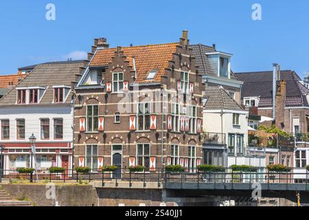 Gorinchem, Niederlande. 25. Juni 2024. Typische Häuser mit rot-weißen Fensterläden am Fenster in der befestigten Stadt Gorinchem entlang der Brücke an Stockfoto
