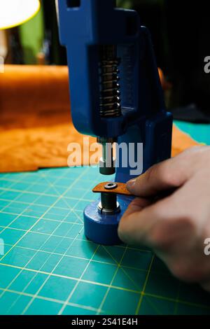 Nahaufnahme der Hände des Meisters, die handgefertigte Lederprodukte nähen. Ein Männerbräuner verbindet die Teile und schafft hochwertige Lederaccessoires. Arbeitsvorgang Stockfoto