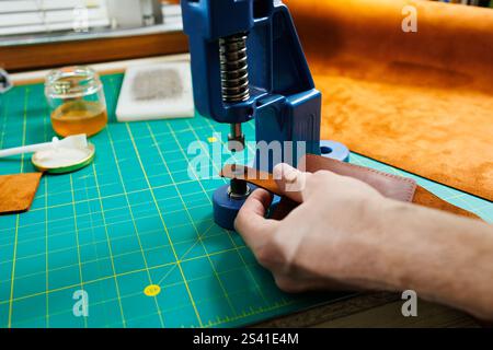 Nahaufnahme der Hände des Meisters, die handgefertigte Lederprodukte nähen. Ein Männerbräuner verbindet die Teile und schafft hochwertige Lederaccessoires. Arbeitsvorgang Stockfoto