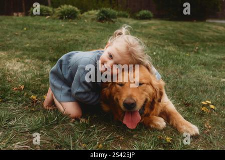 Kleines Mädchen umarmt ihren goldenen Retriever Stockfoto