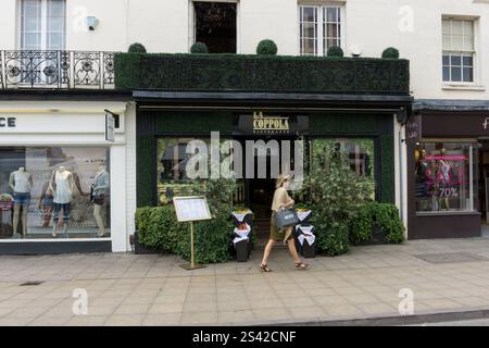 Fassade des La Coppola ein italienisches Restaurant mit mediterraner Einrichtung, Leamington Spa, Warwickshire, Großbritannien; Frau, die vorbeigeht Stockfoto