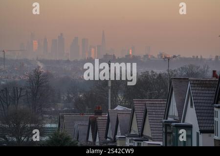 Wimbledon , London 10 Januar 2025 Wohndächer in Wimbledon, Südwesten Londons, bedeckt mit Frost und Blick auf die Skyline der Stadt London unter einem rosa Himmel bei Sonnenaufgang . Das Met Office gibt weitere gelbe Wetterwarnungen für Eis und Schnee mit Temperaturen von bis zu -15 Celsius aus, da Großbritannien seine bisher kälteste Nacht des Jahres verzeichnet hat und in den kommenden Tagen mehr Gefriertemperaturen erwartet werden. Credit.Amer Ghazzal/Alamy Live News Stockfoto