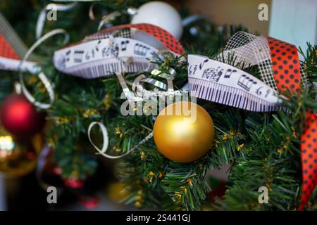 Eine detaillierte Nahaufnahme eines wunderschönen Weihnachtsbaums, der mit bunten Kugeln und eleganten Bändern für die Weihnachtszeit geschmückt ist Stockfoto