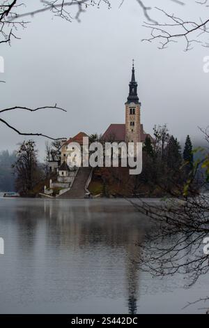 Die Kapelle am Bleder See ist von Bäumen umrahmt und spiegelt sich auf dem Seenwasser Stockfoto