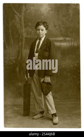 Original-Postkarte aus der Zeit der 1920er Jahre mit einem Schuljungen, der einen Cricketschläger hält, Kricketweiß und Blazer trägt, auf der Tasche sind die Initialen H L aufgestickt. Pat schrieb auf der Rückseite, vielleicht der Name des Jungen. Aus dem Studio von West End Photo Co. Commercial Road, Southampton, Großbritannien, um die 1920er Jahre Stockfoto