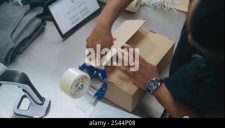 Draufsicht auf den Versand und Empfang von Postfachleuten in Afroamerika Verpackung von Papppaketen mit E-Commerce-Bestellung, Aufklebern, Code scannen, Zustellung vorbereiten. Lagereinrichtung des Postdienstes. Stockfoto