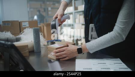 Nahaufnahme der Postangestellten, Versandassistentin, die Kartonpackung mit E-Commerce-Bestellung verpackt, Code scannt, Paket für die Zustellung vorbereitet. Lagereinrichtung, Sortierzentrum des Postdienstes. Stockfoto