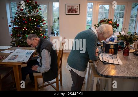 Ältere verheiratete Ehepaare, die beide während der Weihnachtszeit eine britische Zeitung lesen, London, England, Großbritannien Stockfoto