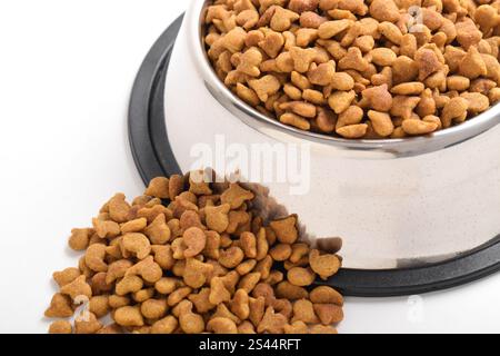 Trockenfutter für Katzen in Schüssel isoliert auf weißem Hintergrund. Braunes Katzenfutter Stockfoto