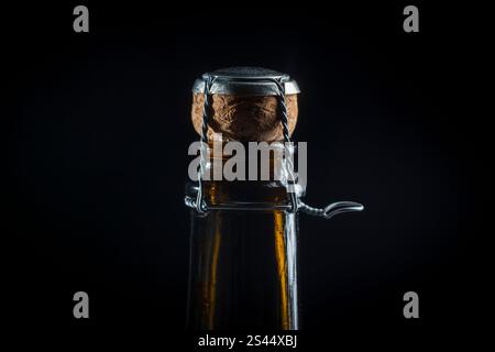 Nahaufnahme eines dunklen Glasflaschenhalses mit Kork und Drahtkäfig auf schwarzem Hintergrund. Bereit für eine festliche Feier. Makrofotografie Stockfoto