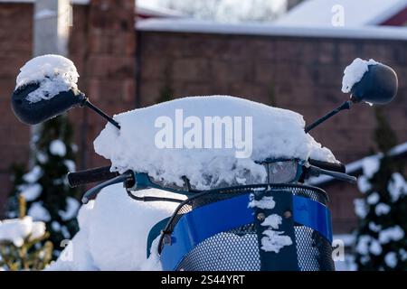 Roller unter Schnee im Hof an einem Wintertag, Nahaufnahme. Teil eines Motorrads, der im Winter mit weißem Schnee bedeckt ist, auf dem Parkplatz, Nahaufnahme Stockfoto