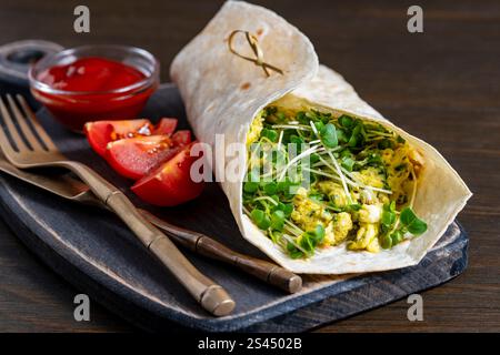Hausgemachte Burrito-Wraps mit Rührei-Omelett und Mikrogrün für gesundes Frühstück auf Holzbrett, Nahaufnahme Stockfoto