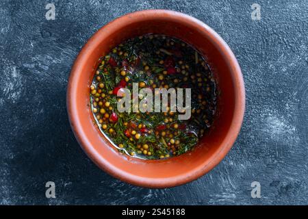 Scharfe Soße für Fisch oder Fleisch aus rotem Chili, Senf, Olivenöl, Sojasauce und grünem Dill in einer Keramiksoße auf dunklem Hintergrund, Draufsicht Stockfoto