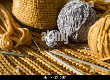 Gestrickter Korb aus gelbem Garn. Auf dem Tisch befinden sich eine Fadenkugel und Stricknadeln. Handgefertigt. Stockfoto