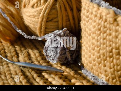 Gestrickter Korb aus gelbem Garn. Auf dem Tisch befinden sich eine Fadenkugel und Stricknadeln. Handgefertigt. Stockfoto