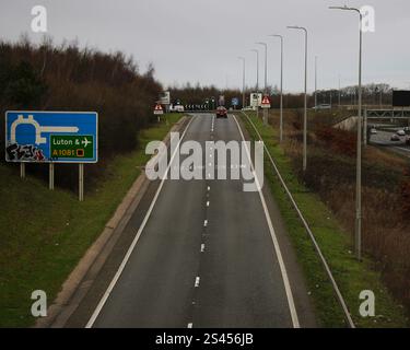 M1 Autobahn-Abfahrt an einem grauen Tag in Richtung London Luton Airport mit Graffiti-Kunst auf dem Autobahnschild Stockfoto