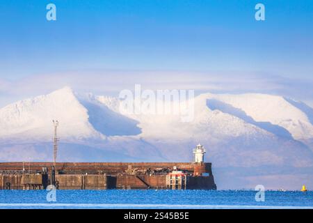 Troon, Großbritannien. Januar 2025. Blick westlich von Barassie Beach, Troon, Ayrshire, Schottland, Großbritannien, über Troon Pier und Leuchtturm zum schneebedeckten Goatfell Gipfel auf der Isle of Arran, 32 Meilen entfernt, über den Firth of Clyde. Goatfell ist ein Corbett (2874 m hoch), der höchste Gipfel auf Arran und ist bei Bergwanderern und Touristen beliebt. Quelle: Findlay/Alamy Live News Stockfoto