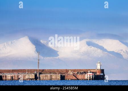 Troon, Großbritannien. Januar 2025. Blick westlich von Barassie Beach, Troon, Ayrshire, Schottland, Großbritannien, über Troon Pier und Leuchtturm zum schneebedeckten Goatfell Gipfel auf der Isle of Arran, 32 Meilen entfernt, über den Firth of Clyde. Goatfell ist ein Corbett (2874 m hoch), der höchste Gipfel auf Arran und ist bei Bergwanderern und Touristen beliebt. Quelle: Findlay/Alamy Live News Stockfoto