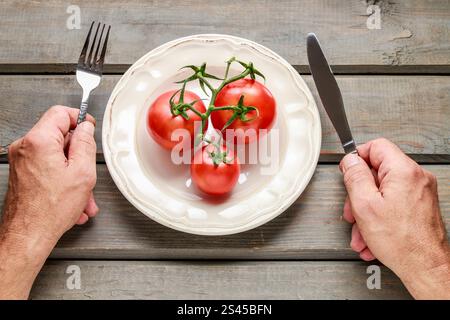 Das konzeptionelle Bild des Menschen, der rote Tomaten isst. Gesunde Ernährung Stockfoto