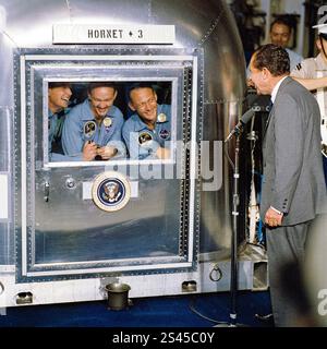 US-Präsident Richard Nixon (1913–1994) begrüßte die Astronauten Neil Armstrong, Buzz Aldrin und Michael Collins am 24. Juli 1969 durch das Fenster ihrer Mobile Quarantine Facility (MQF) an Bord der USS Hornet nach ihrer erfolgreichen Landung auf dem Mond und Rückkehr zur Erde. Stockfoto