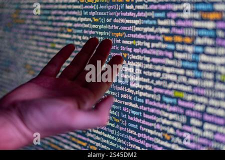 Das Bild zeigt eine Person, die mit einem großen, farbcodierten Programmierungsdisplay, möglicherweise Python, interagiert und dabei Handgesten verwendet, während sie sich auf die Code-Manipulation konzentriert Stockfoto