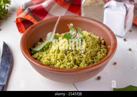 Couscous in Schüssel mit Olivenöl und getrockneten Tomaten auf weißem Hintergrund, orientalische Küche Stockfoto