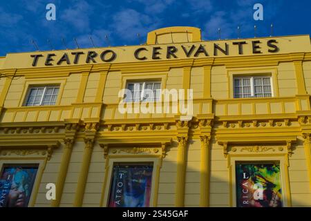 Eine Nahaufnahme eines gelben Gebäudes mit den Worten „Teatro Cervantes“ in großen, fetten Buchstaben über dem Eingang. Das Gebäude hat eine klassisch verzierte Fassade Stockfoto