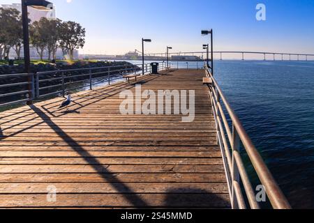 Ein Pier mit einer Brücke im Hintergrund. Der Pier ist aus Holz und hat ein paar Vögel Stockfoto