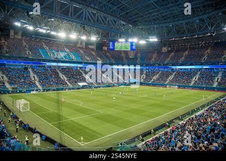 Football match on the soccer field, fans are sitting in the stands, football players are running on the green ground Stockfoto
