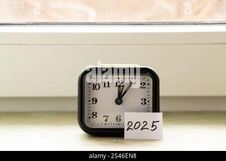 Am Fenster eines Hauses stehen ein Tischwecker und eine Papierkarte mit dem Text 2025 Stockfoto