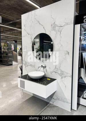 Kiew, Ukraine - 10. Januar 2025: Modernes Badezimmer mit rundem Spiegel, Wand in Marmor-Optik und einem stilvollen, schwebenden Kosmetikbereich mit einem Innenraum Stockfoto