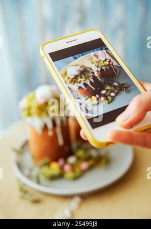 Foodbloger macht Fotos mit einem modernen Smartphone. Paska - das süße Osterbrot mit Zuckerglasur, dekoriert mit essbarem „Moos“-Stillleben. Beliebtes dess Stockfoto