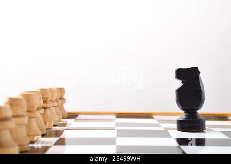 Schachritter vor gegnerischen Bauern auf Schachbrett auf weißem Hintergrund Stockfoto