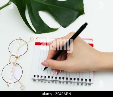 Frau Hand Nahaufnahme Notizen im Planer. Weibliche Schreiben mit Stift Informationen, Erinnerungen, Zeitplan in Tagebuch. Handschrift. Hochwertige Fotos Stockfoto