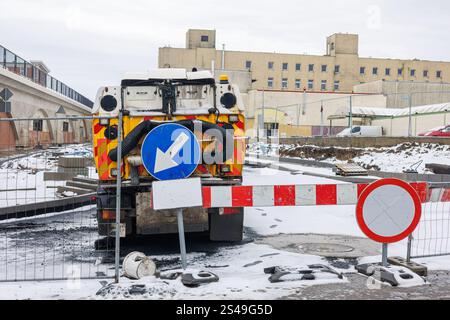 Zäune und Straßenschilder vor einer stehenden Kehrmaschine und Straßenwaschmaschine auf einer Baustelle. Stockfoto