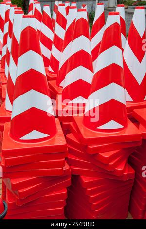Eine Kollektion brandneuer, in leuchtend orange und weiß gestreifter Verkehrskegel in Stapeln ist ein interessantes Konzeptbild für Kunst, Design oder Vorsicht in Japan Stockfoto