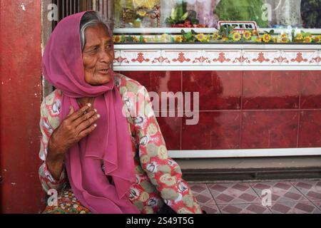 Eine schöne alte Frau in einem rosafarbenen Kleid mit einem rosa Hijab oder Kopftuch in Bukittinggi, West Sumatra, Indonesien. Stockfoto