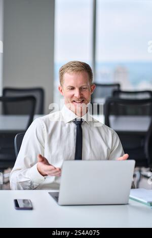 Glücklicher, beschäftigter junger Geschäftsmann, der ein virtuelles Meeting im Büro hat. Stockfoto