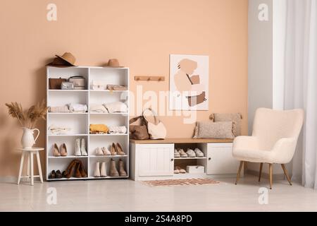 Stilvolle Einrichtung des Ankleidezimmers mit gefalteter Kleidung, Schuhen und Accessoires Stockfoto
