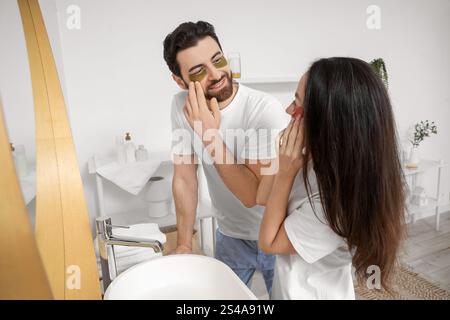 Liebevolles Paar, das im Bad Flecken unter den Augen aufträgt Stockfoto
