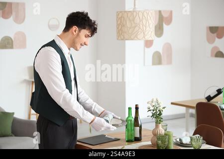 Männlicher Kellner, der einen Tisch im Restaurant abdeckt Stockfoto