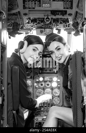 Zwei schöne Frauen Pilot tragen Uniform. Blick auf die Kamera durch das Cockpit. Piloten im Cockpit. Mädchen, die die Kamera betrachten. Glücklich und erfolgreich Stockfoto